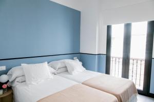 een slaapkamer met een groot wit bed met blauwe muren bij Pasaje Zamora Apartamentos in Sevilla