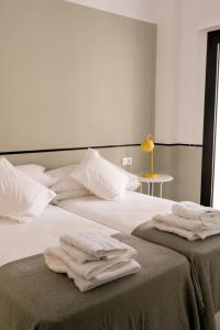 - une chambre avec 2 lits et des serviettes dans l'établissement Pasaje Zamora Apartamentos, à Séville