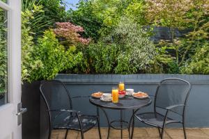 a table with two chairs and two cups of orange juice at The Resident Kensington in London
