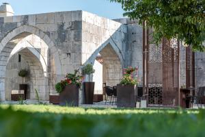 um edifício de pedra com dois arcos com vasos de plantas em Heritage Hotel Maskovica Han em Pakoštane