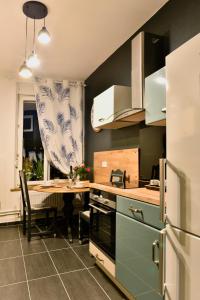 a kitchen with a table and a refrigerator at MoonLOVE, SPA/Sauna et Jacuzzi privés, charme et détente. in Nancy