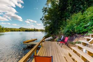 a dock with two chairs and a boat on the water at Lake Eden Escape in Eden