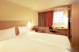 a bedroom with a large white bed and a desk at Ibis Évry-Courcouronnes in Evry-Courcouronnes