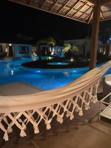 a hammock in front of a swimming pool at night at AWARA POUSADA BOUTIQUE in São Miguel do Gostoso