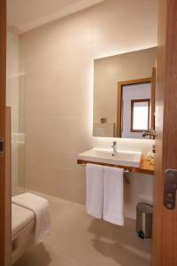Grand Boutique Hotel في بريشتيني: حمام أبيض مع حوض ومرآة