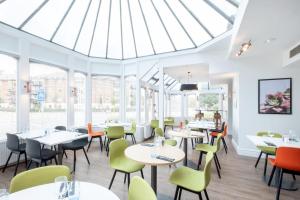 a dining room with tables and chairs and a skylight at Holiday Inn Farnborough, an IHG Hotel in Farnborough