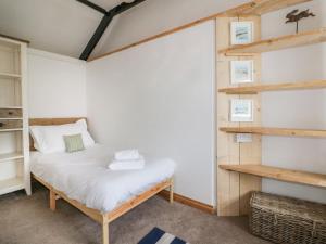 a small bedroom with a bed and shelves at Trenant Cottage in Fowey