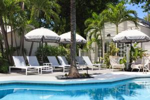 einen Pool mit Stühlen und Sonnenschirmen neben einem Haus in der Unterkunft Lighthouse Hotel - Key West Historic Inns in Key West