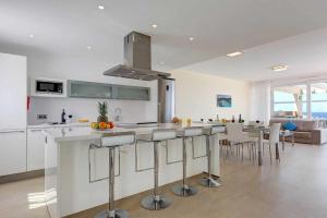 a kitchen and living room with a counter and chairs at Villa TURQUESA MAR in Cala en Forcat