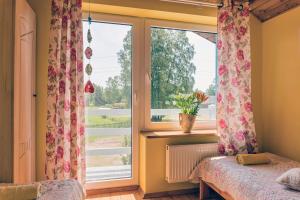 Dom na Starym Gościńcu Tiszyna في Dubicze Cerkiewne: غرفة نوم مع نافذة مع الزهور على الستائر