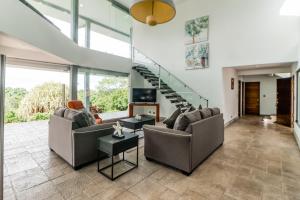 una sala de estar con 2 sofás y una escalera en Casa Cariblanco, en Tarcoles