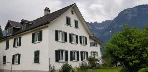 Casa blanca con persianas verdes y montaña en Casa Margerita, en Flums