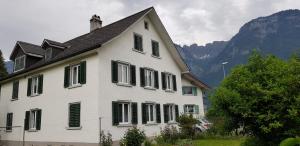 a white house with green shutters and a mountain at Casa Margerita in Flums