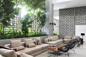 a lobby with a couch and chairs and plants at Bell Suites Moka in Sepang