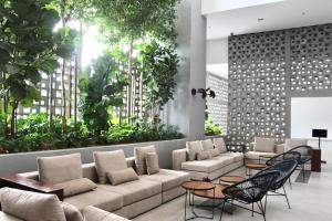 a lobby with a couch and chairs and plants at Bell Suites @ Sunsuria City in Sepang