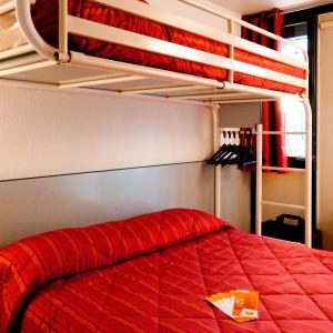 a bedroom with a bed with a red comforter at Premiere Classe Gueret in Guéret