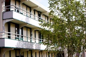 un immeuble d'appartements avec balcon et arbre dans l'établissement Premiere Classe Gueret, à Guéret