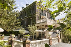 una casa grande con una valla blanca delante de ella en Belle Isle Sur Risle - Chateau Hotel & Spa, en Pont-Audemer