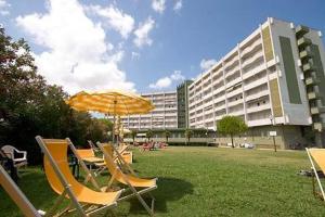 um grupo de cadeiras e um guarda-sol e um edifício em Jet Residence Agenzia Riviera del Conero em Porto Recanati
