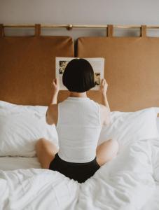 a woman sitting on a bed reading a book at The Masons Arms Hotel in Louth