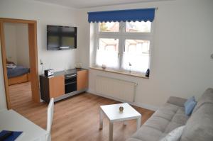 a living room with a couch and a tv at Hotel Südstrand Amrum in Wittdün