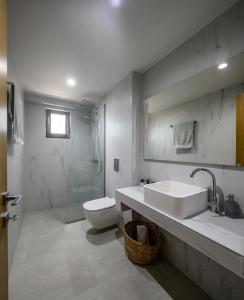 biała łazienka z umywalką i toaletą w obiekcie NOA BEACHFRONT SUITES w Kardamenie +26 zdjęć