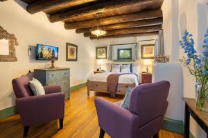a bedroom with a bed and two chairs at Inn of the Turquoise Bear in Santa Fe