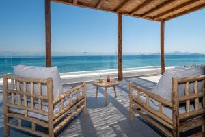 dwa krzesła i stół na werandzie z widokiem na ocean w obiekcie NOA BEACHFRONT SUITES w Kardamenie