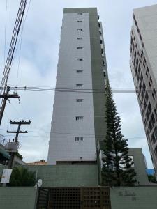 ein hohes weißes Gebäude mit einem Baum davor in der Unterkunft Excelente Apto em Área HOSPITALAR - St Joana, R Portugues, Memorial, Hope, Hapvida in Recife