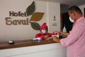 a man with a child wearing a mask sitting at a counter at Hotel Saval Jerico in Jericó