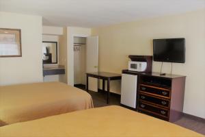 um quarto de hotel com duas camas e uma televisão em Oregon Trail Inn and Suites em Lakeview