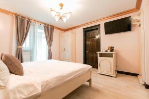 a bedroom with a white bed and a television at Vila Genia in Câmpulung Moldovenesc