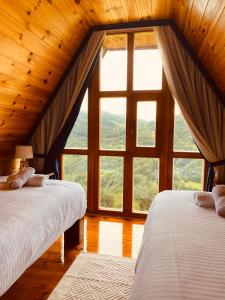 2 Betten in einem Zimmer mit einem großen Fenster in der Unterkunft FERN FARM ECO RESORT in Mojkovac