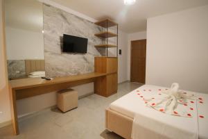 a bedroom with a bed and a desk and a television at Hotel Four Islands in Ksamil
