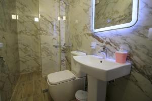 W łazience znajduje się umywalka, toaleta i lustro. w obiekcie Hotel Four Islands w mieście Ksamil
