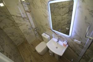a bathroom with a toilet and a sink and a mirror at Hotel Four Islands in Ksamil