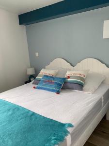 Una cama blanca con almohadas encima. en Maisonnette de la mer, en Hermanville-sur-Mer