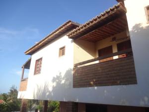 a white house with a roof and a brick wall at Bela Vista in Canoa Quebrada