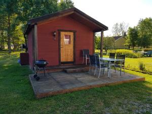 a small red house with a table and a grill at Stuga in Romakloster