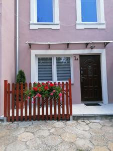 a pink house with a wooden fence with flowers at Apartament Grosik in Duszniki Zdrój