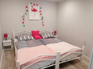 a bedroom with a white bed with pink accents at Apartament Grosik in Duszniki Zdrój
