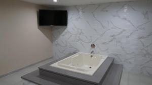 
a white bath tub sitting inside of a bathroom at Sea Breeze Inn - LAX Airport, Los Angeles in Inglewood
