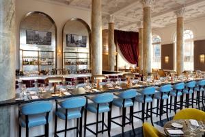 eine lange Bar in einem Restaurant mit blauen Stühlen in der Unterkunft Riggs Washington DC in Washington