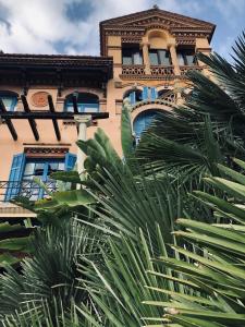 a building with blue windows and palm trees in front of it at Hotel Boutique Mas Passamaner in La Selva del Camp