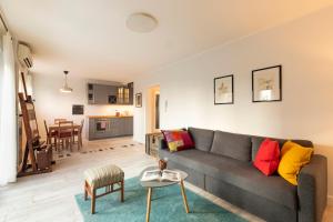 a living room with a gray couch and a kitchen at Apartment Paha-Paha modern & full of light with free parking in Rijeka