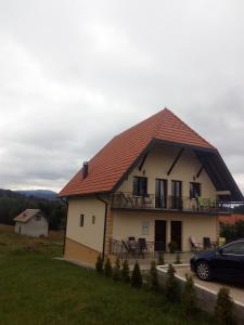 a house with a roof with a car parked in front at Apartmani Tarsko Sunce in Kaludjerske Bare