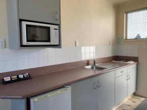a kitchen with a microwave and a sink at Temuka Motel in Temuka