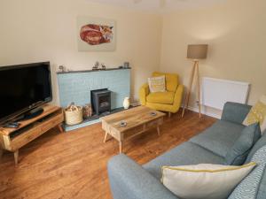 a living room with a couch and a tv at Rainforest Cottage in Cinderford