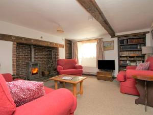 a living room with red chairs and a fireplace at Forge Cottage in West Lulworth