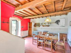 DicomanoにあるBelvilla by OYO Appealing Holiday Home with poolの赤い壁のキッチン(木製のテーブルと椅子付)